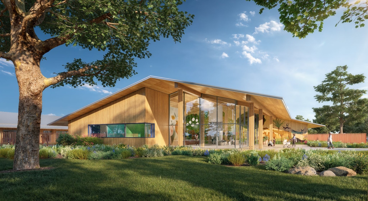 A wooden building with a large glass front is surrounded by landscaping.