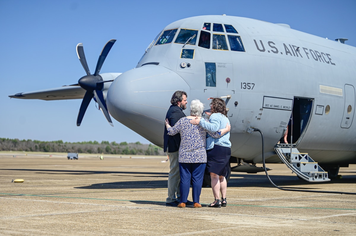 Family members hug in front of a static display of a C-130J Super Hercules aircraft at Little Rock Air Force Base, Arkansas, March 12, 2025. Family members of fallen crew members Capt. Richard Couture and Capt. Kevin Kelleher were able to tour the 62nd Airlift Squadron and 314th Aircraft Maintenance Squadron, providing them a firsthand look at the lasting impact left by their loved ones.
