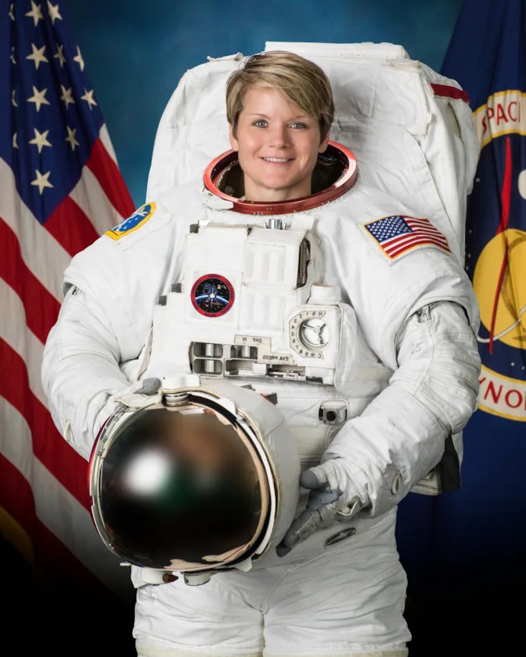 A woman is posing in an astronaut suit, holding a helmet.