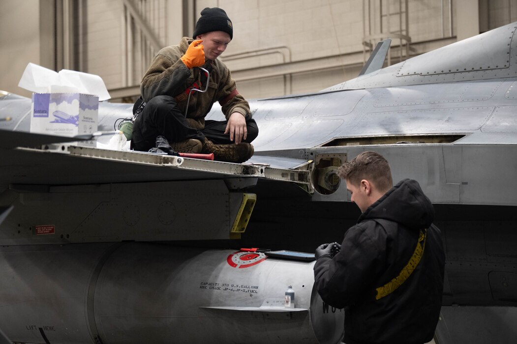 U.S. Air Force Senior Airmen Aidan Wampler, left, and Therron Rude, right, 18th Fighter Generation Squadron crew chiefs inspect and prepare to replace a flaperon of an F-16 Fighting Falcon at Eielson Air Force Base, Alaska, March 4, 2025.