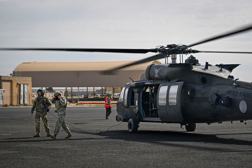 Two military members walk away from a U.S. Army UH-60 Blackhawk helicopter.