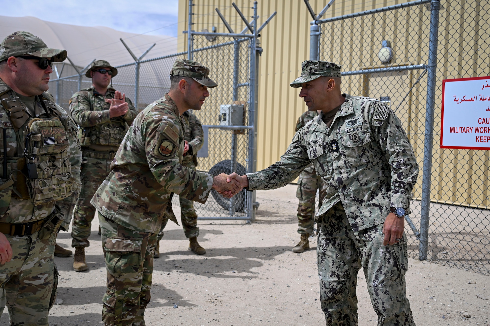 Two military members shake hands.