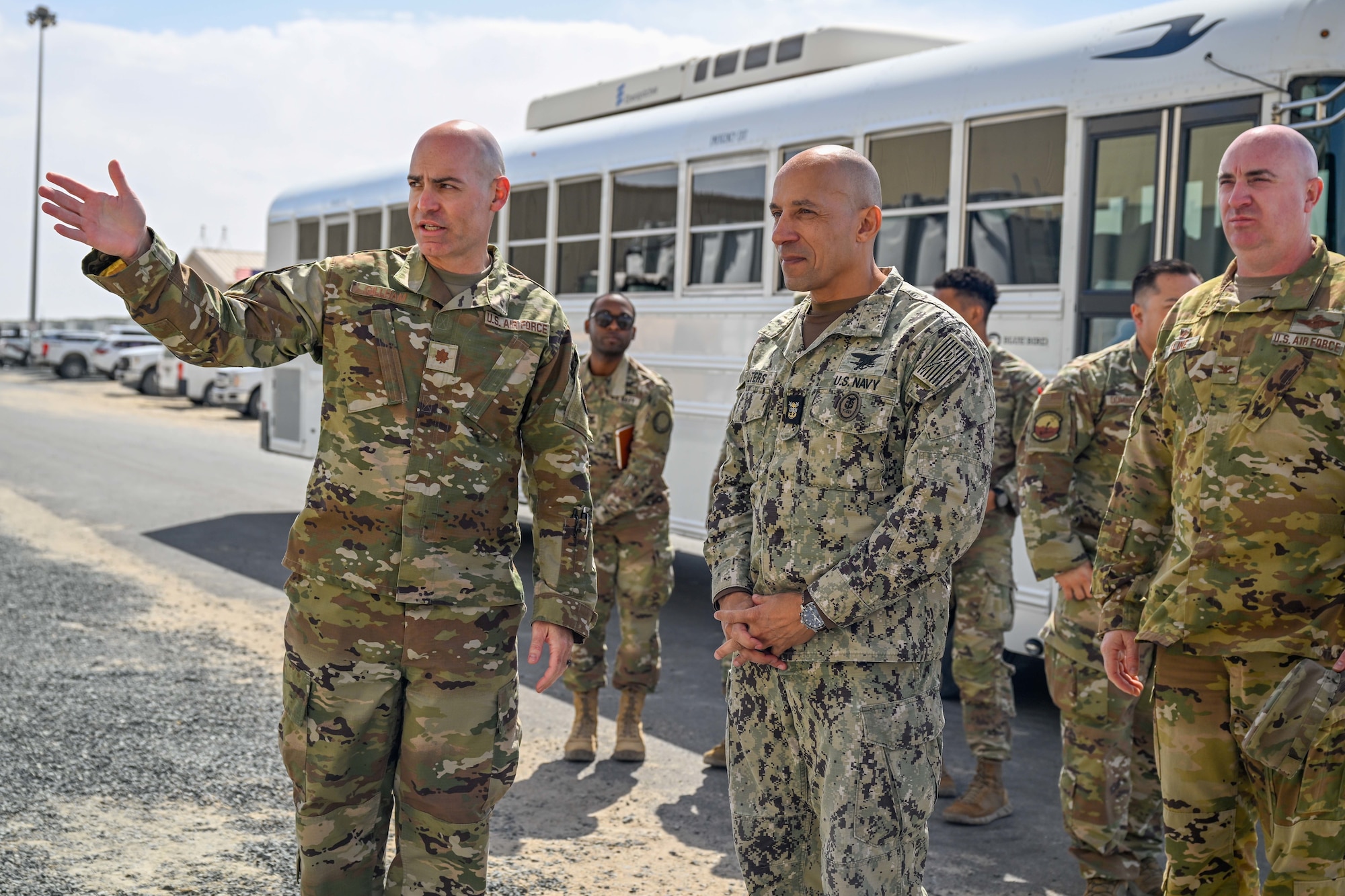 Three military members talk together outside.