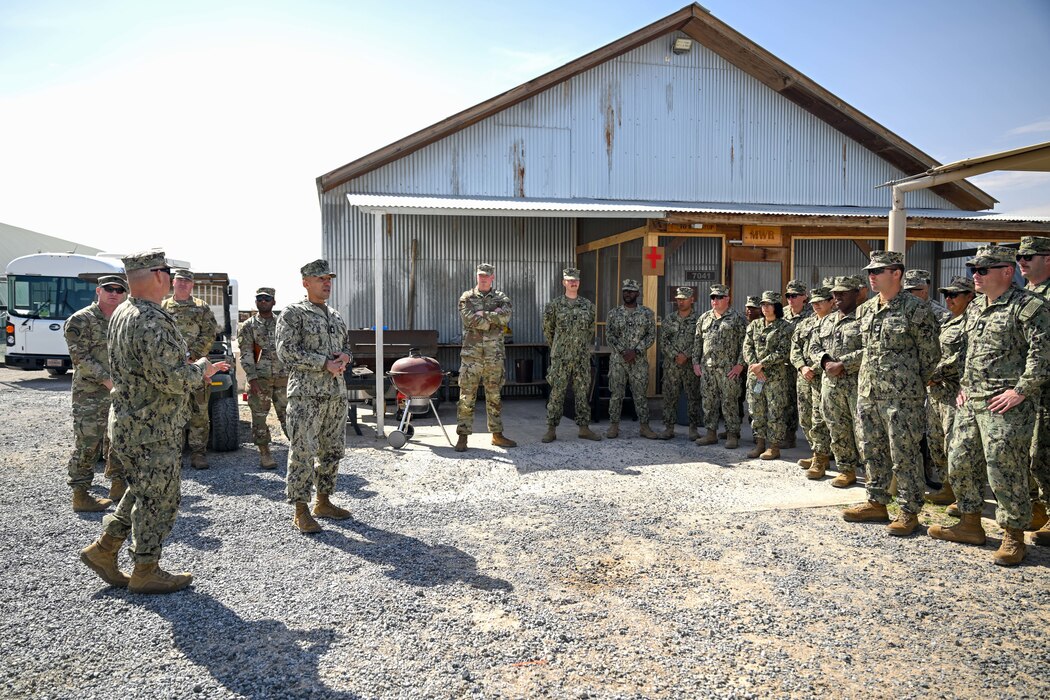 A group of military members talk together outside.