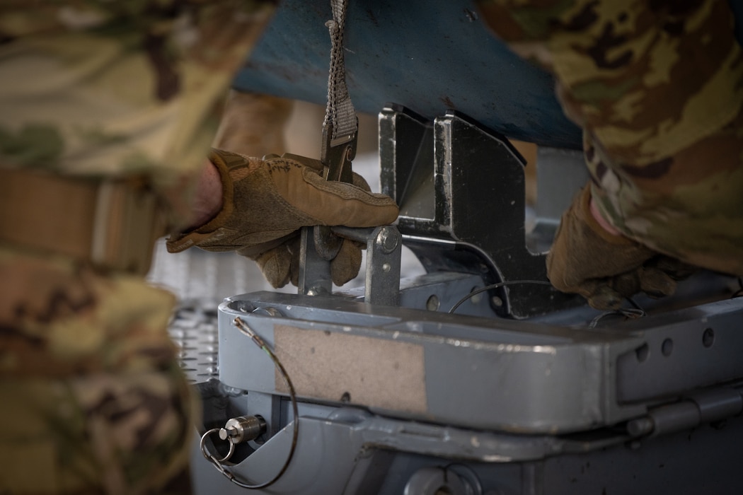 A U.S. Air Force Airman removes a strap from a munition.