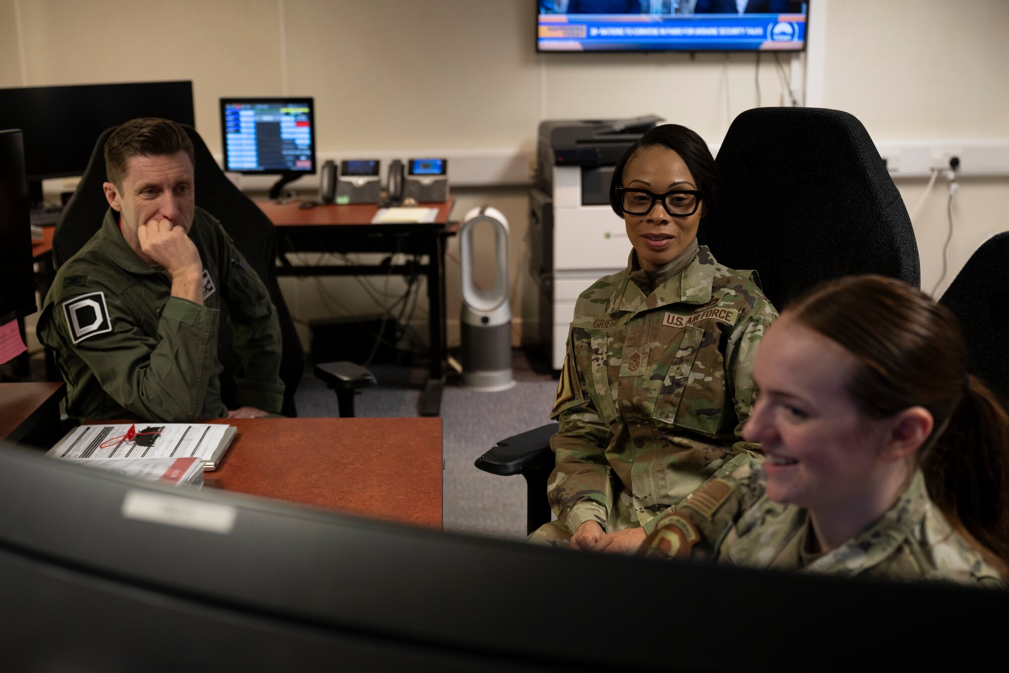 U.S. Air Force Col. Ryan Garlow, left, 100th Air Refueling Wing commander, Chief Master Sgt. Tiffany Griego, 100th ARW command chief, center, and Airman 1st class Anna Smith, 100th ARW Command Post emergency actions controller, review procedures on how to report mishaps at RAF Mildenhall, England, Mar. 11, 2025. Smith showcased daily command post operations during a Day in the Life immersion with the ARW command team. (U.S. Air Force photo by Senior Airman Nash Truitt)