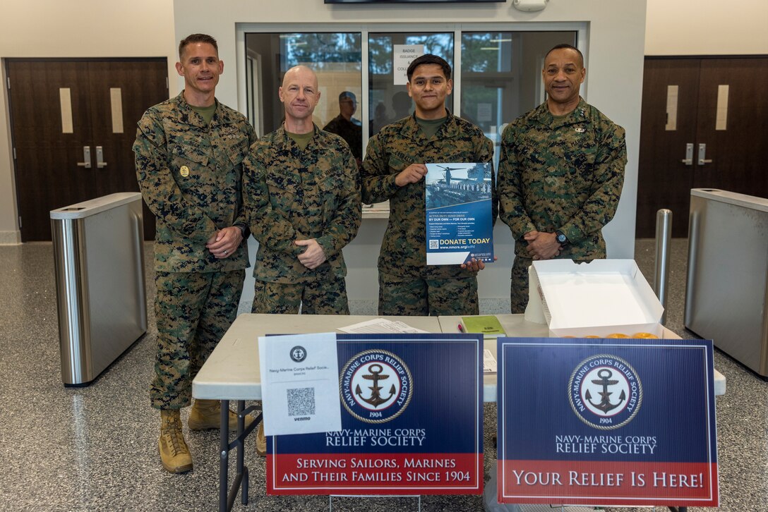 From left to right, U.S. Navy Command Master Chief Petty Officer John Beck, II Marine Expeditionary Force (II MEF) Command Master Chief, Sgt. Maj. David A. Wilson, II MEF command senior enlisted leader, Lance Cpl. Jose A. Carballo, administrative specialist, and Lt. Gen. Calvert L. Worth Jr., II MEF commanding general pose for a photo during a Navy-Marine Corps Relief Society (NMCRS) fundraiser at Marine Corps Base Camp Lejeune, North Carolina, March 10, 2025. The NMCRS provides financial, educational, and emotional assistance to active-duty and retired Sailors, Marines, and their families, supporting them in times of need and promoting their well-being. (U.S. Marine Corps photo by Lance Cpl. John Allen)
