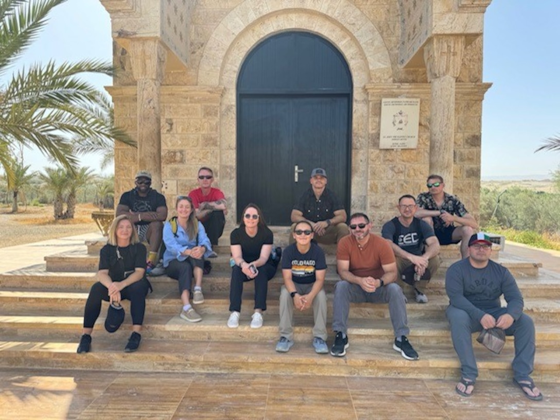 Group of people sitting down for a photo in front of a monument in Kuwait City, Kuwait.