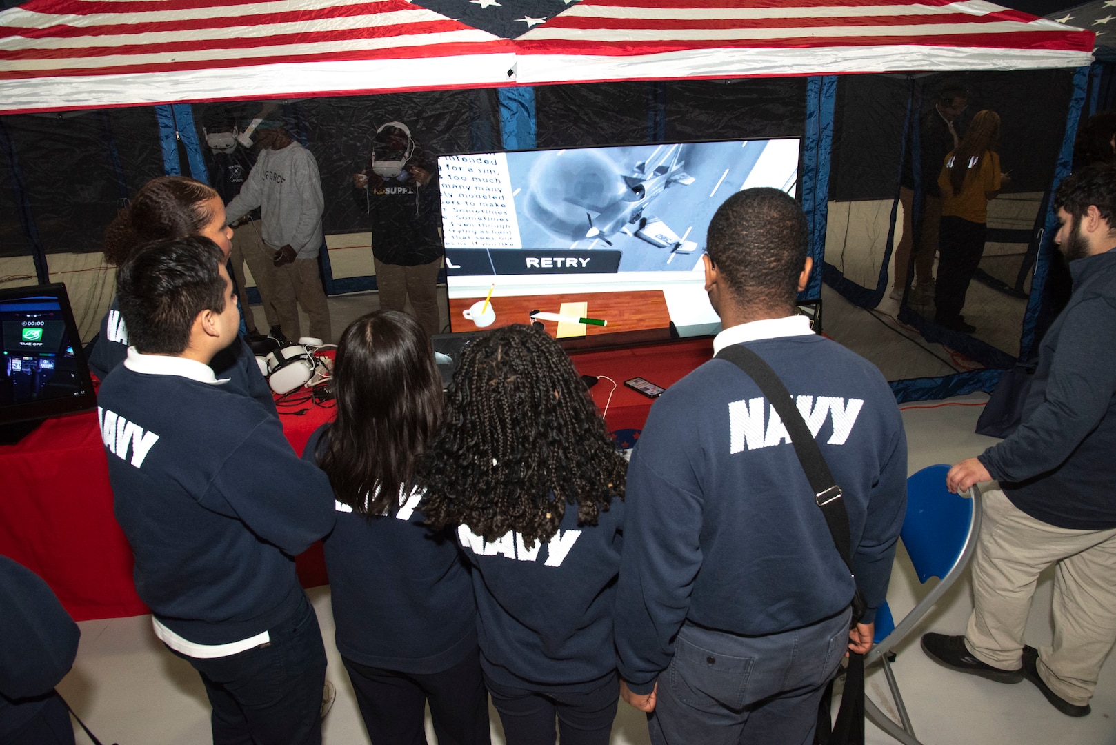 Local high school students gather to listen to closing remarks by Treniece Terry, Defense Threat Reduction Agency technical engagements program manager, during the Seventh Annual Aerospace Summit at Joint Base Andrews, Md., March 4, 2025. The 1st Helicopter Squadron provided a UH-1N Huey for static display, enabling students the opportunity to view the helicopter close-up. (U.S. Air Force photo by Patrick Griffith)