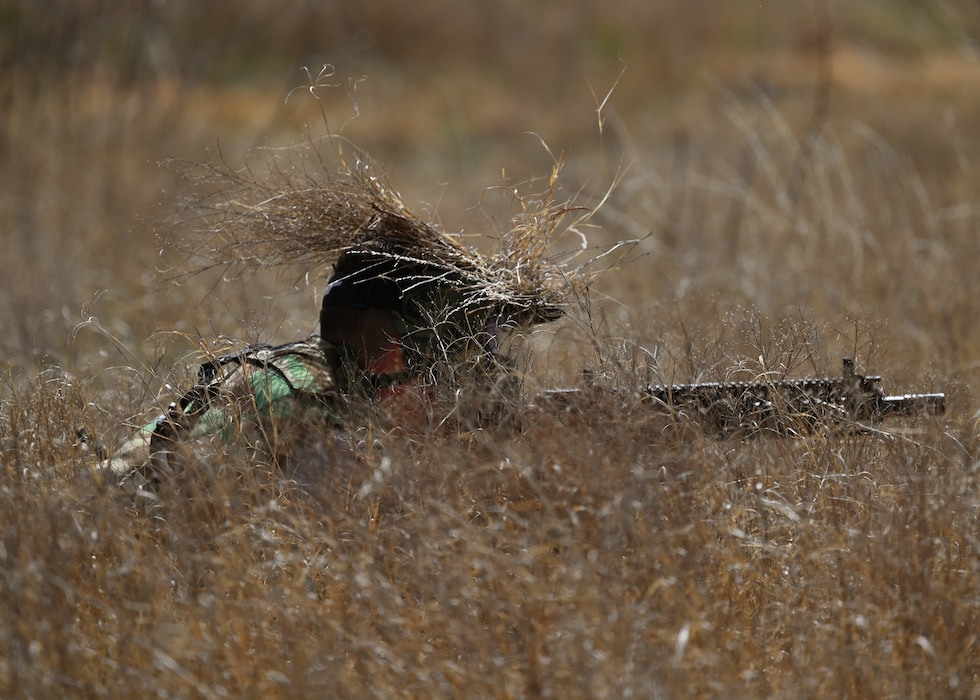 A U.S. Marine assigned to Goodfellow Air Force Base simulating lies in the grass waiting to ambush Angelo State University ROTC Air Force Detachment 847 cadets during their search and rescue operation at the field training exercise on Goodfellow AFB, Texas, March 7, 2025. Marines acted as opposing forces for the cadets and volunteered their time to assist in training them for real-world situations. (U.S. Air Force photo by Staff Sgt. Nathan Call)