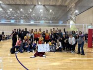 people gathered on the volleyball court for a group photo