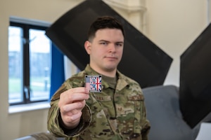 U.S. Air Force Staff Sgt. Ethan Oliva, 373rd Training Squadron hydraulic instructor, holds a 100th Air Refueling Wing commander’s coin at RAF Mildenhall, England, March 12, 2025.