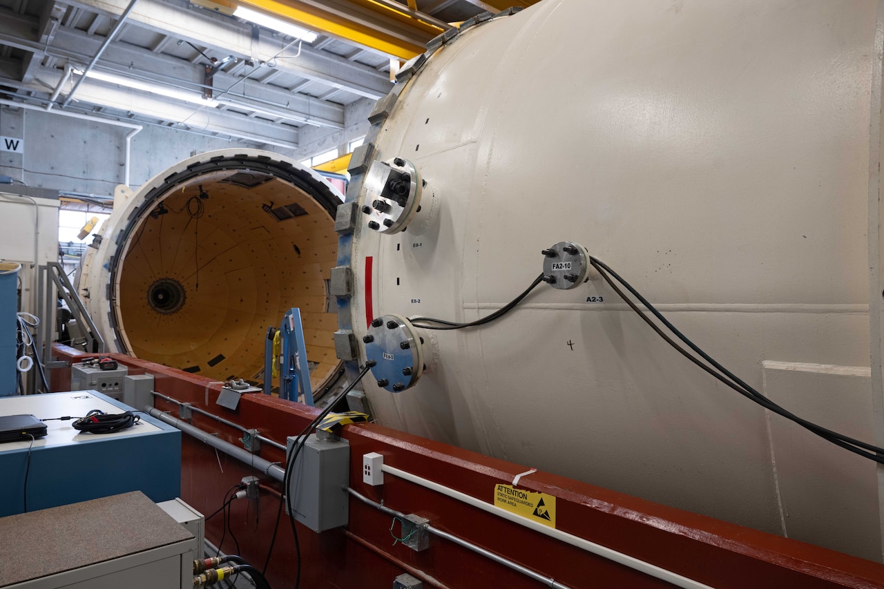 A massive pressure chamber sits open and empty.