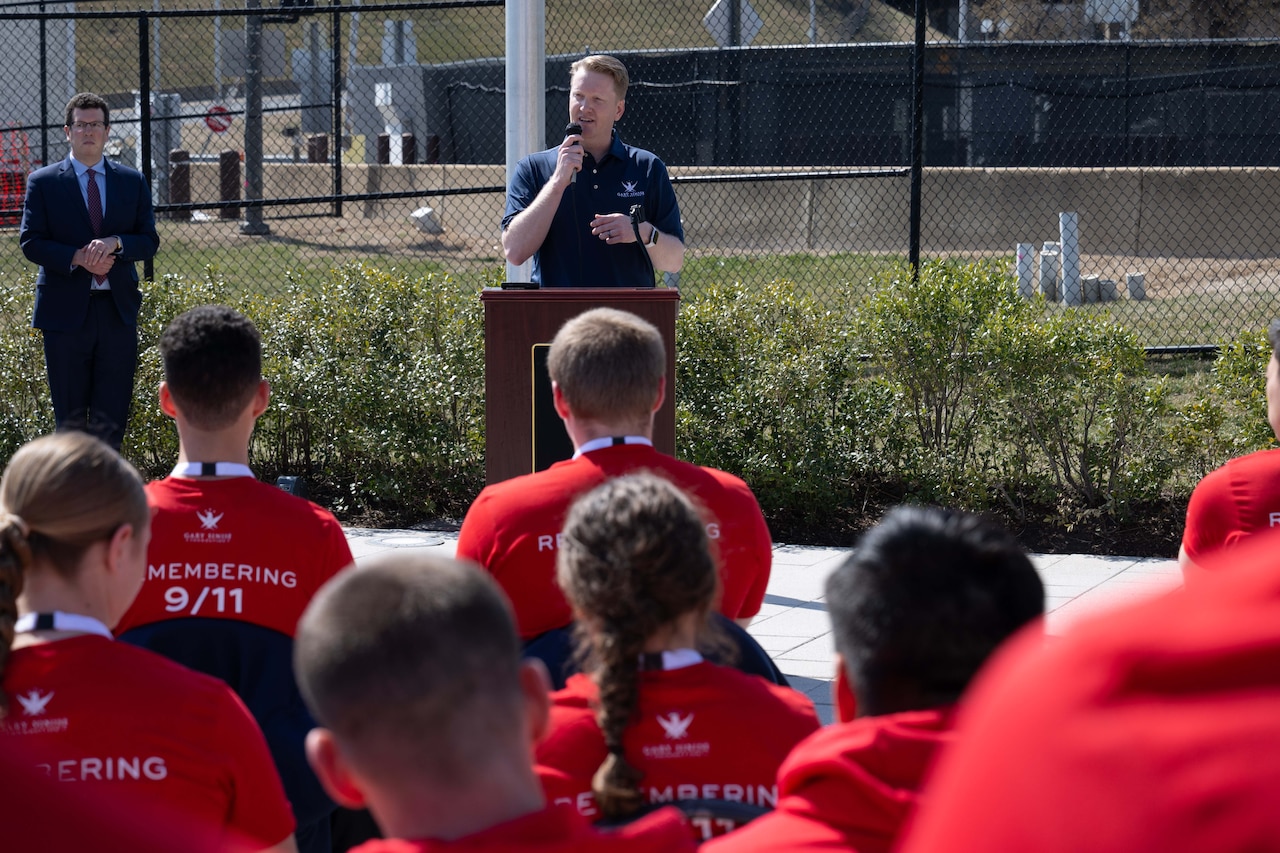 Students watch a man behind a podium speak.