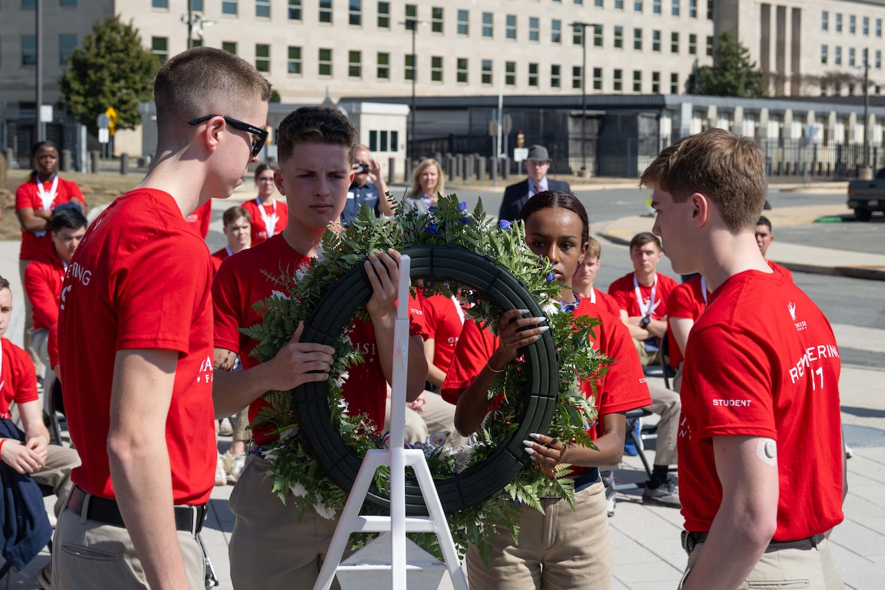 Students lay a wreath on a stand.