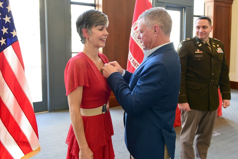 Joanne Mann, U.S. Army Corps of Engineers Nashville District executive officer and congressional liaison, receives her retirement pin from her husband David during a ceremony March 12, 2025, at the Nashville Public Library in Nashville, Tennessee. (USACE Photo by Lee Roberts)