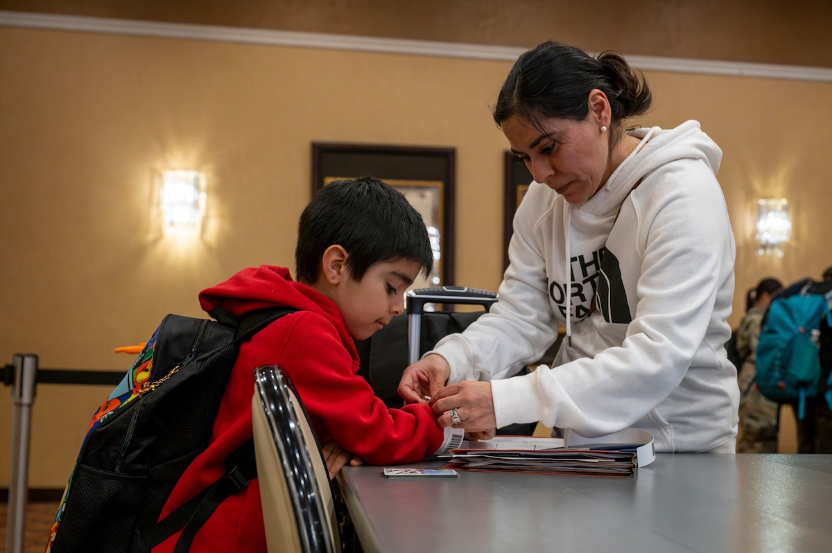 A family participating in the Emergency Evacuation Program (EEP) exercise puts on identification wristbands at Misawa Air Base, Japan, Mar. 11, 2025.