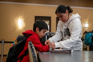 A family participating in the Emergency Evacuation Program (EEP) exercise puts on identification wristbands at Misawa Air Base, Japan, Mar. 11, 2025.
