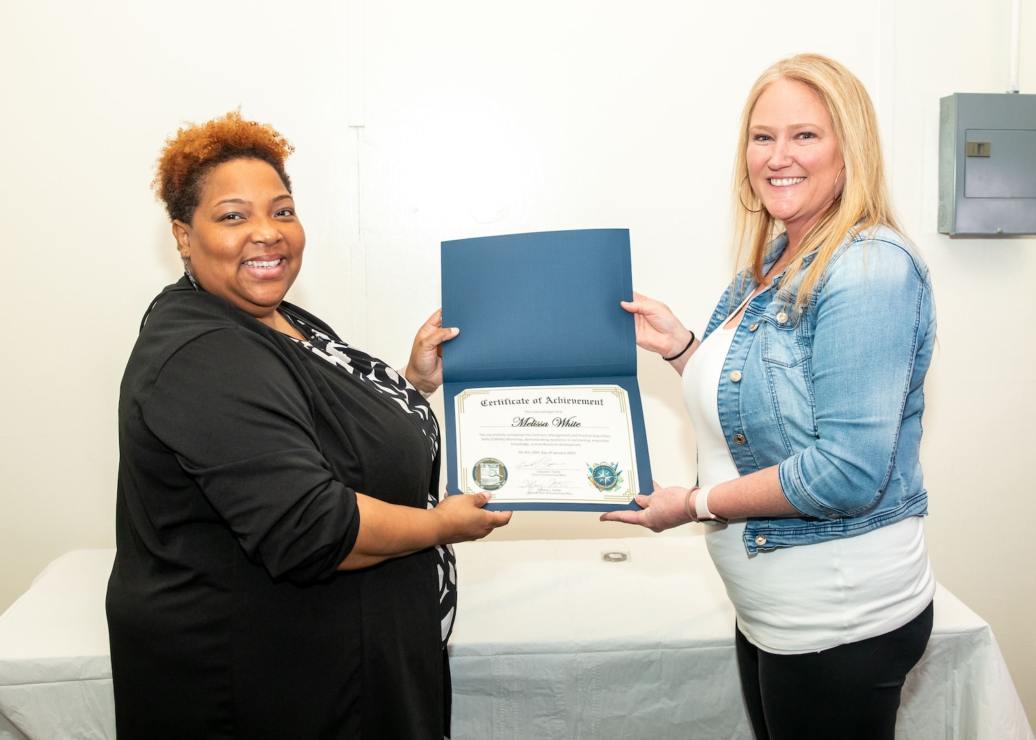 Norfolk Naval Shipyard Contracting Department Business Operation Division Head Donyette Rodgers (left) presents the Contracts Management & Practical Acquisition Skills (CMPAS) Workshop completion certificate to Contract Specialist Melissa White. White was one of nine to attend the inaugural 13-week program, which consisted of over 100 hours of academic instruction and 50 hours of hands-on training through mock procurements.