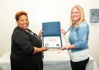 Norfolk Naval Shipyard Contracting Department Business Operation Division Head Donyette Rodgers (left) presents the Contracts Management & Practical Acquisition Skills (CMPAS) Workshop completion certificate to Contract Specialist Melissa White. White was one of nine to attend the inaugural 13-week program, which consisted of over 100 hours of academic instruction and 50 hours of hands-on training through mock procurements.