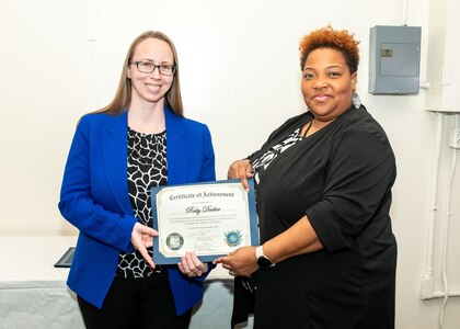 Norfolk Naval Shipyard Contracting Department Contract Specialist Ruby Decker (right) receives her certificate of completion, for the inaugural class of Contracts Management & Practical Acquisition Skills (CMPAS) Workshop, from the Contracting Department Business Operation Division Head Donyette Rodgers. Decker was one of nine to attend the 13-week program, which consisted of over 100 hours of academic instruction and 50 hours of hands-on training through mock procurements.