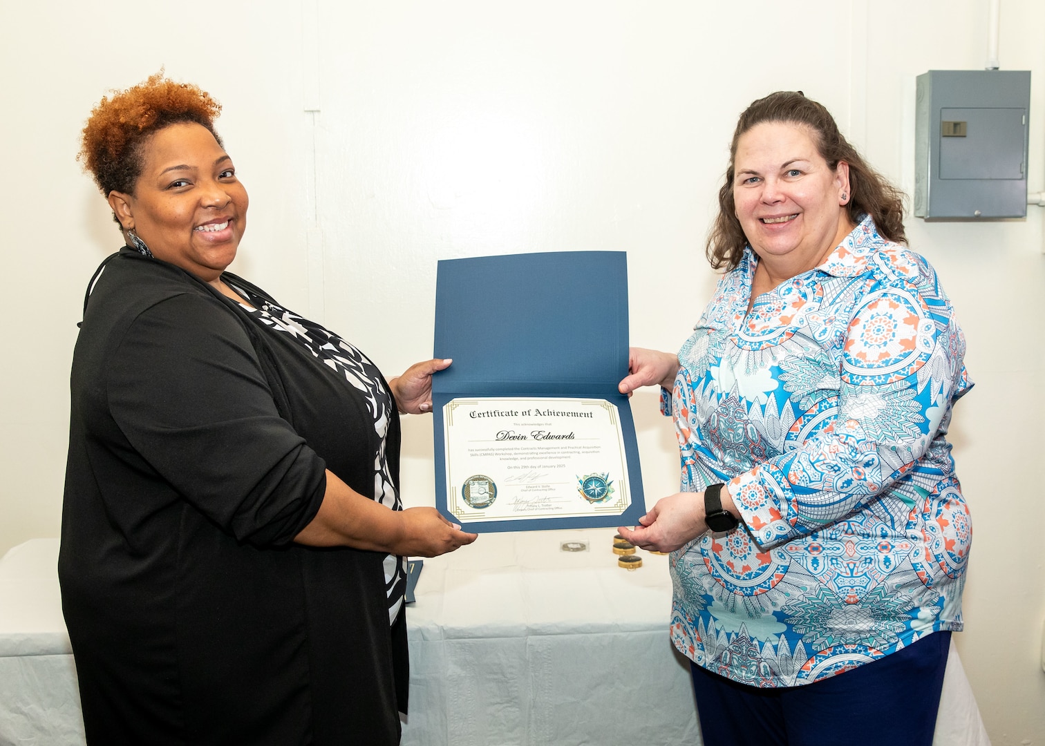 Norfolk Naval Shipyard Contracting Department Business Operation Division Head Donyette Rodgers (left) presents the Contracts Management & Practical Acquisition Skills (CMPAS) Workshop completion certificate to Contract Specialist Denise Swain (right) on behalf of Contract Specialist Devin Edwards. Edwards was one of nine to attend the inaugural 13-week program, which consisted of over 100 hours of academic instruction and 50 hours of hands-on training through mock procurements.