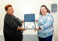 Norfolk Naval Shipyard Contracting Department Business Operation Division Head Donyette Rodgers (left) presents the Contracts Management & Practical Acquisition Skills (CMPAS) Workshop completion certificate to Contract Specialist Denise Swain (right) on behalf of Contract Specialist Devin Edwards. Edwards was one of nine to attend the inaugural 13-week program, which consisted of over 100 hours of academic instruction and 50 hours of hands-on training through mock procurements.
