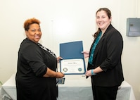 Norfolk Naval Shipyard Contracting Department Business Operation Division Head Donyette Rodgers (left) presents the Contracts Management & Practical Acquisition Skills (CMPAS) Workshop completion certificate to Contract Specialist Jordan Moore. Moore was one of nine to attend the inaugural 13-week program, which consisted of over 100 hours of academic instruction and 50 hours of hands-on training through mock procurements.
