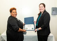 Norfolk Naval Shipyard Contracting Department Business Operation Division Head Donyette Rodgers (left) presents the Contracts Management & Practical Acquisition Skills (CMPAS) Workshop completion certificate to Contract Specialist Jordan Moore. Moore was one of nine to attend the inaugural 13-week program, which consisted of over 100 hours of academic instruction and 50 hours of hands-on training through mock procurements.