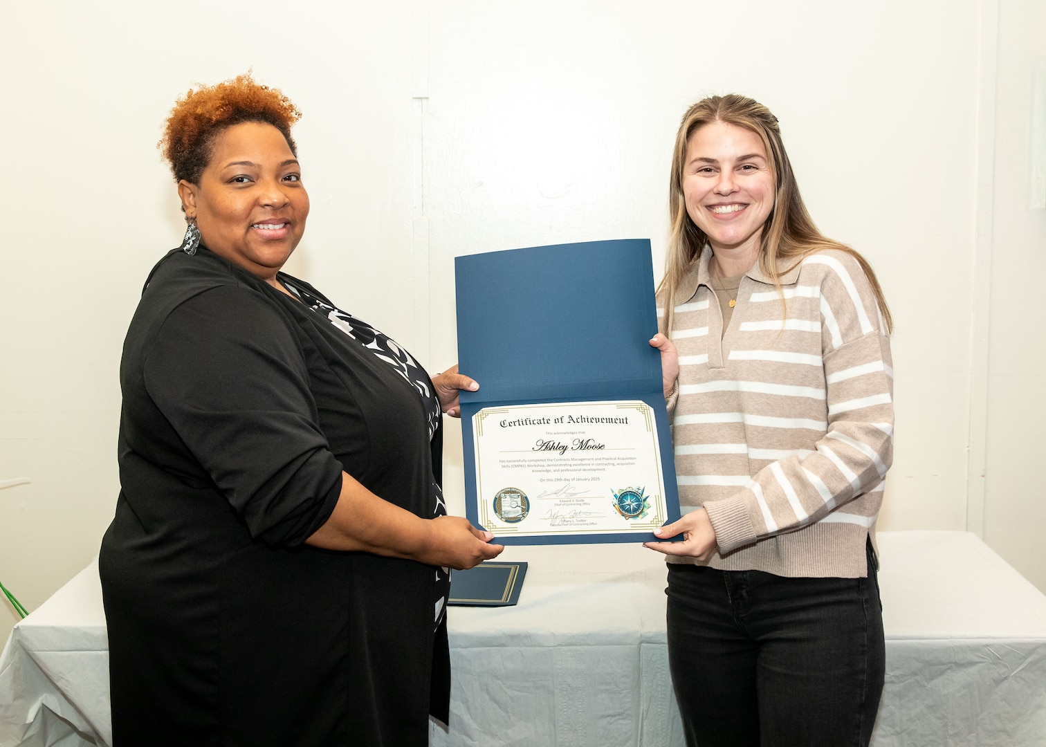 Norfolk Naval Shipyard Contracting Department Business Operation Division Head Donyette Rodgers (left) presents the Contracts Management & Practical Acquisition Skills (CMPAS) Workshop completion certificate to Contract Specialist Ashley Moose. Moose was one of nine to attend the inaugural 13-week program, which consisted of over 100 hours of academic instruction and 50 hours of hands-on training through mock procurements.