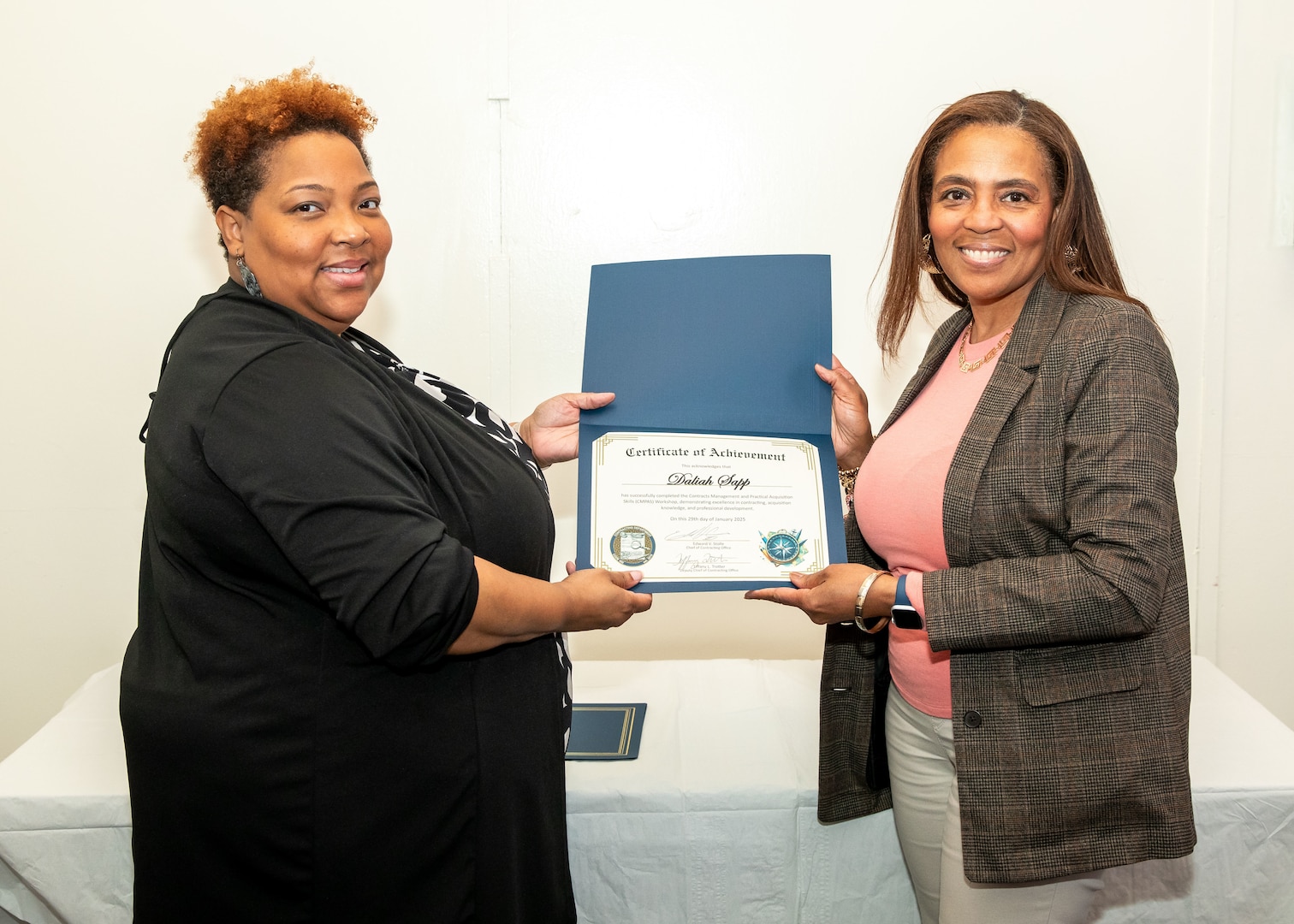 Norfolk Naval Shipyard Contracting Department Business Operation Division Head Donyette Rodgers (left) presents the Contracts Management & Practical Acquisition Skills (CMPAS) Workshop completion certificate to Purchasing Agent Daliah Maxwell Sapp. Sapp was one of nine to attend the inaugural 13-week program, which consisted of over 100 hours of academic instruction and 50 hours of hands-on training through mock procurements.