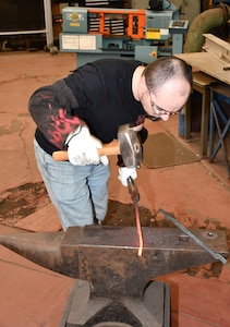 Norfolk Naval Shipyard Metal Forging Shop (Shop 11F) Metal Forger Jesse Dalton was first introduced to blacksmithing when he was 12-years-old. “I started playing World of Warcraft and the character I created was a blacksmith,” said Dalton. “At the time I didn’t know everything a blacksmith did, so I started Googling and found it very interesting. This led me to become a member of the Tidewater Blacksmiths Guild, learning how to blacksmith seven years before enrolling in NNSY’s apprenticeship program for metal forging.”
