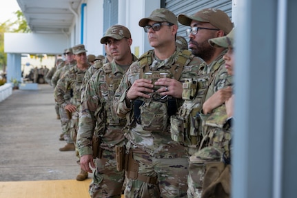 U.S. Airmen assigned to the 156th Contingency Response Group, Puerto Rico Air National Guard, listen to instructions for tactical gear issue during the Mothball 2 Combat Readiness Exercise at Muñiz Air National Guard Base, Carolina, Puerto Rico, March 7, 2025. The exercise measured  the 156th Wing’s ability to generate, employ and sustain contingency response capabilities in a war-fighting scenario.