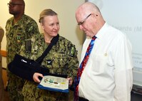 JOINT BASE SAN ANTONIO-FORT SAM HOUSTON – (March 13, 2025) – Dr. John Simecek, director, Craniofacial Health and Restorative Medicine (CHRM), was awarded the Civilian Service Commendation Medal by Naval Medical Research Unit (NAMRU) San Antonio Commanding Officer Capt. Jennifer Buechel, Nurse Corps, during an All Hands Meeting held at the Battlefield Health and Trauma Research Institute. Simecek, a retired Naval dentist, joined the Navy in 1972 serving for 23 years and retired at the rank of lieutenant commander. He joined NAMRU San Antonio in 2009 and has served as the CHRM director for 11 years. He will be retiring from federal service in the fall and will miss the camaraderie. NAMRU San Antonio is one of eight research laboratories within Naval Medicine Research and Development.  Its mission is to conduct gap driven combat casualty care, craniofacial, and directed energy research to improve survival, operational readiness, and safety of Department of Defense personnel engaged in routine and expeditionary operations. (U.S. Navy photo by Burrell Parmer, NAMRU San Antonio Public Affairs/Released)