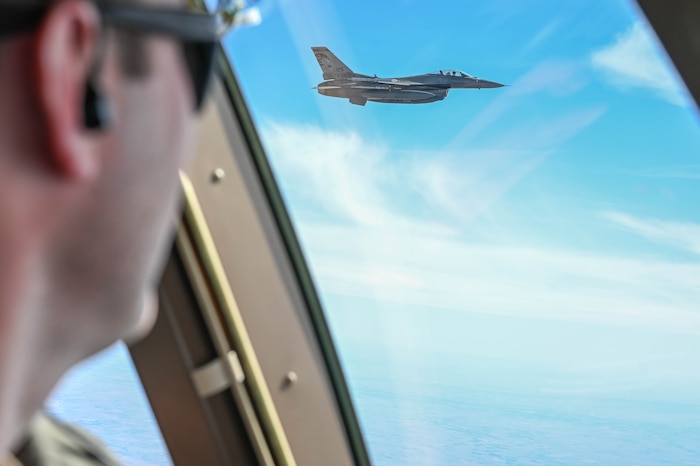 A man watches a military jet fly.