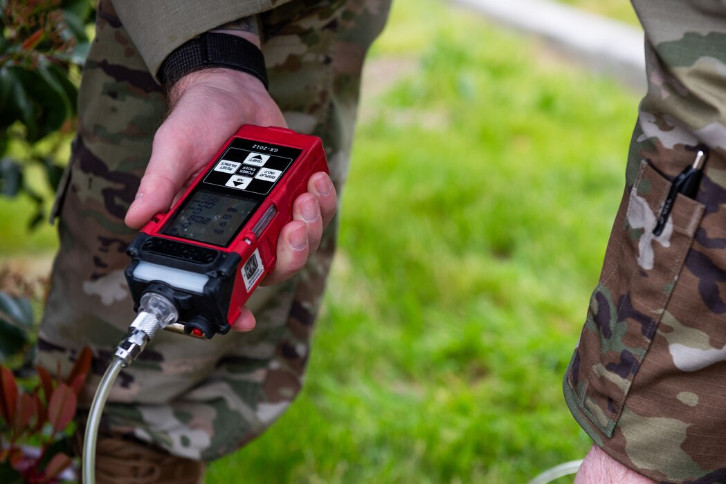 An Airman uses an atmospheric tester to check the air quality in a manhole for confined space safety training