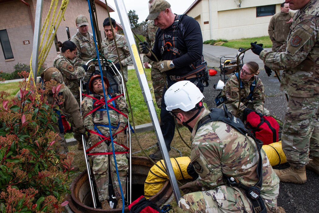 An airman is pulled from a man hole in a basket as part of training
