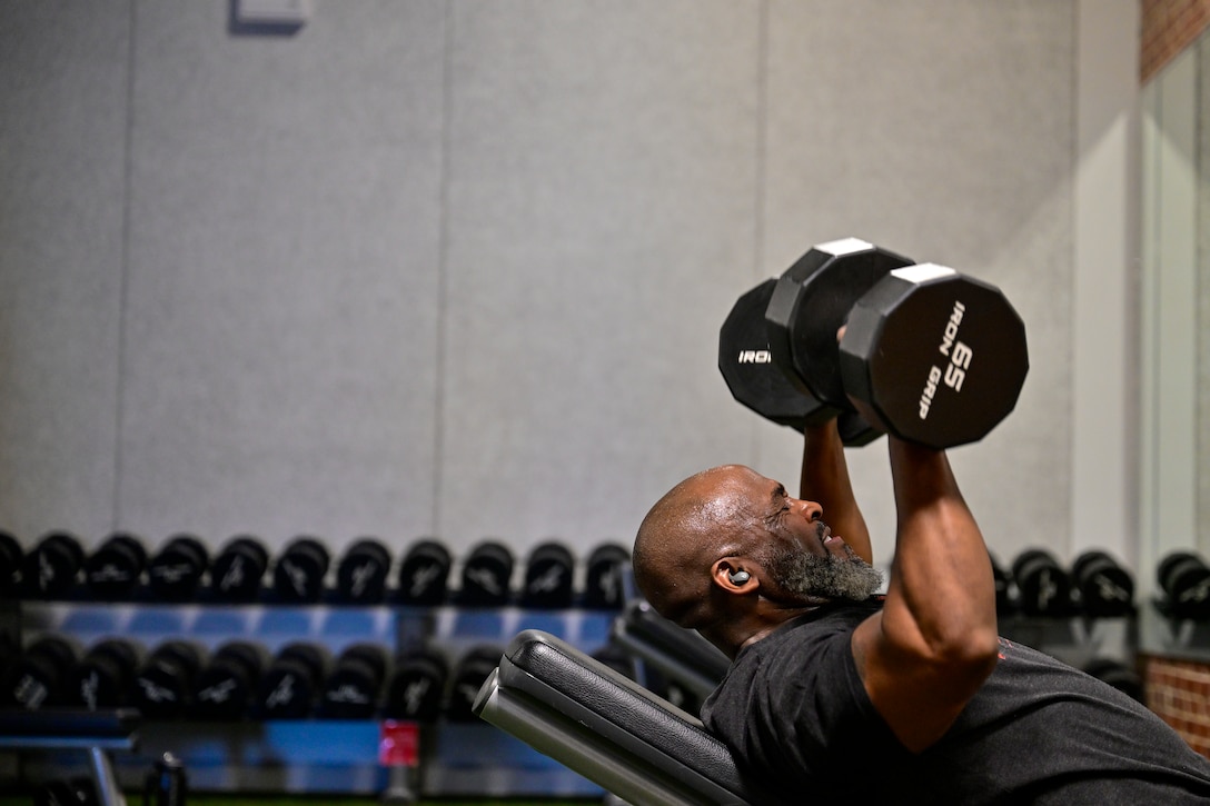 Man lays on bench and lifts weights