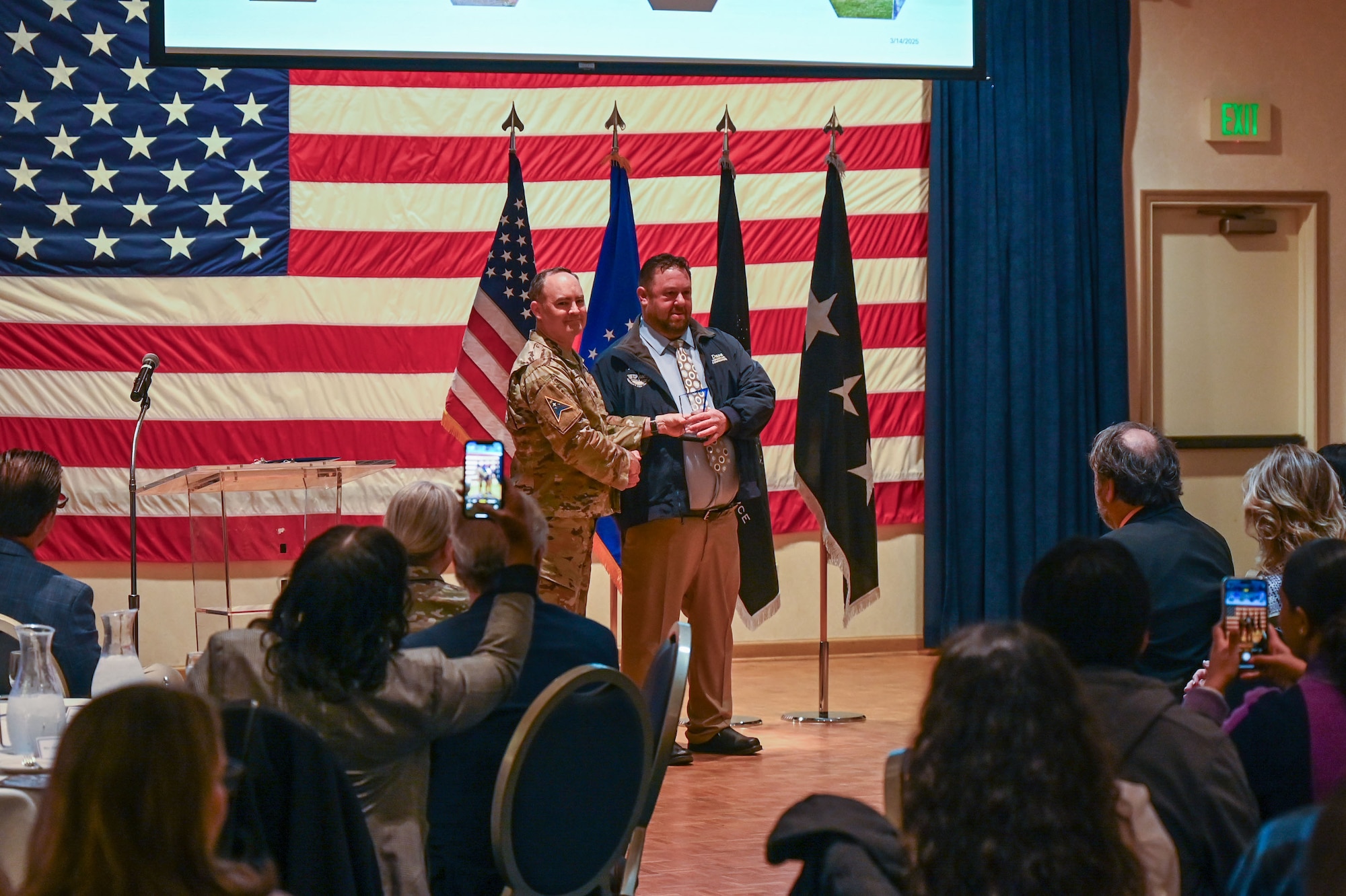 Two men stand on stage posing for a photo.
