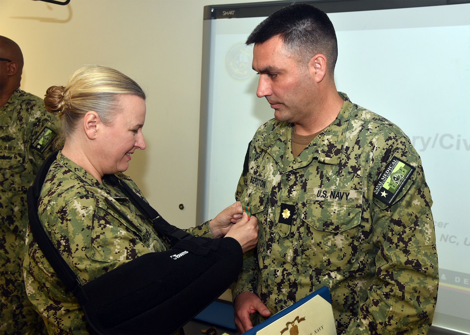 JOINT BASE SAN ANTONIO-FORT SAM HOUSTON – (March 13, 2025) – Lt. Cmdr. Jeffrey Biberston, Medical Corps, of Casper, Wyo,, epartment head, Expeditionary and Trauma Medicine, was awarded the Navy and Marine Corps Achievement Medal by Naval Medical Research Unit (NAMRU) San Antonio Commanding Officer Capt. Jennifer Buechel during an All Hands Meeting held at the Battlefield Health and Trauma Research Institute. Biberston, was recently selected as NAMRU San Antonio’s Junior Officer of the Year for 2024 and is the only Pulmonary and Critical Care physician currently serving within Naval Medicine Research and Development (NMR&D). NAMRU San Antonio is one of eight research laboratories within NMR&D. Its mission is to conduct gap driven combat casualty care, craniofacial, and directed energy research to improve survival, operational readiness, and safety of Department of Defense personnel engaged in routine and expeditionary operations. (U.S. Navy photo by Burrell Parmer, NAMRU San Antonio Public Affairs/Released)