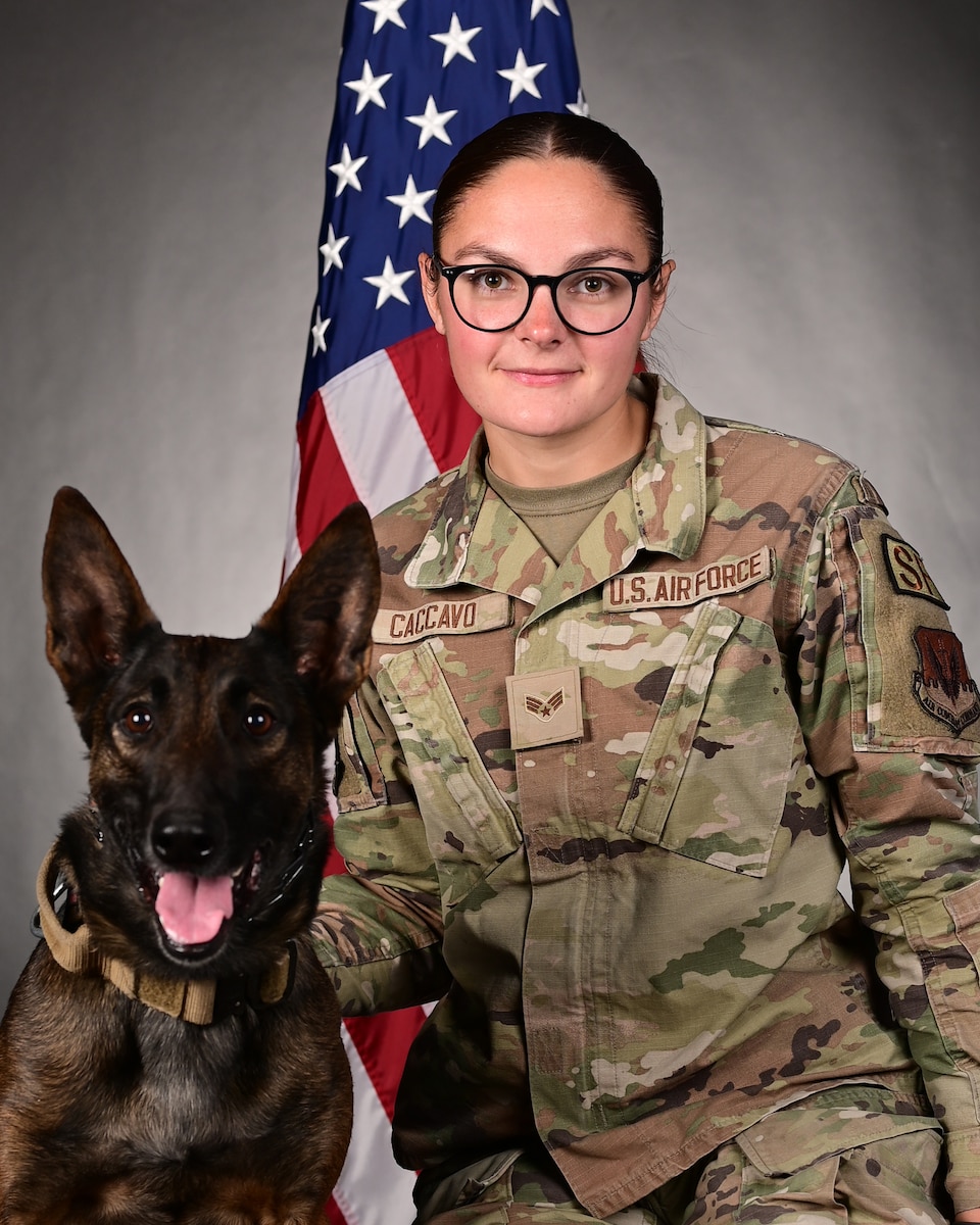 A military working dog handler and K9 pose for a photo.