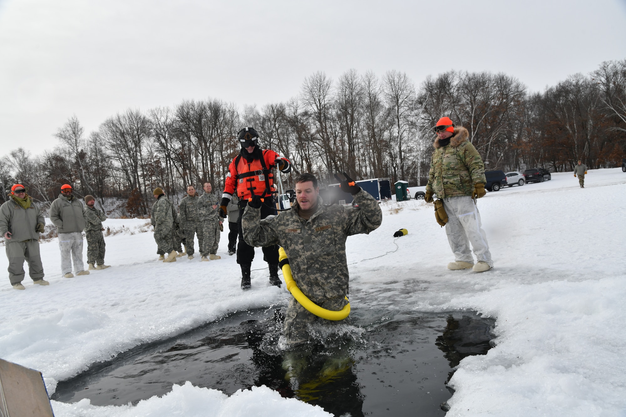 A man steps into an icy pool of water that is carved into a snowy lake.