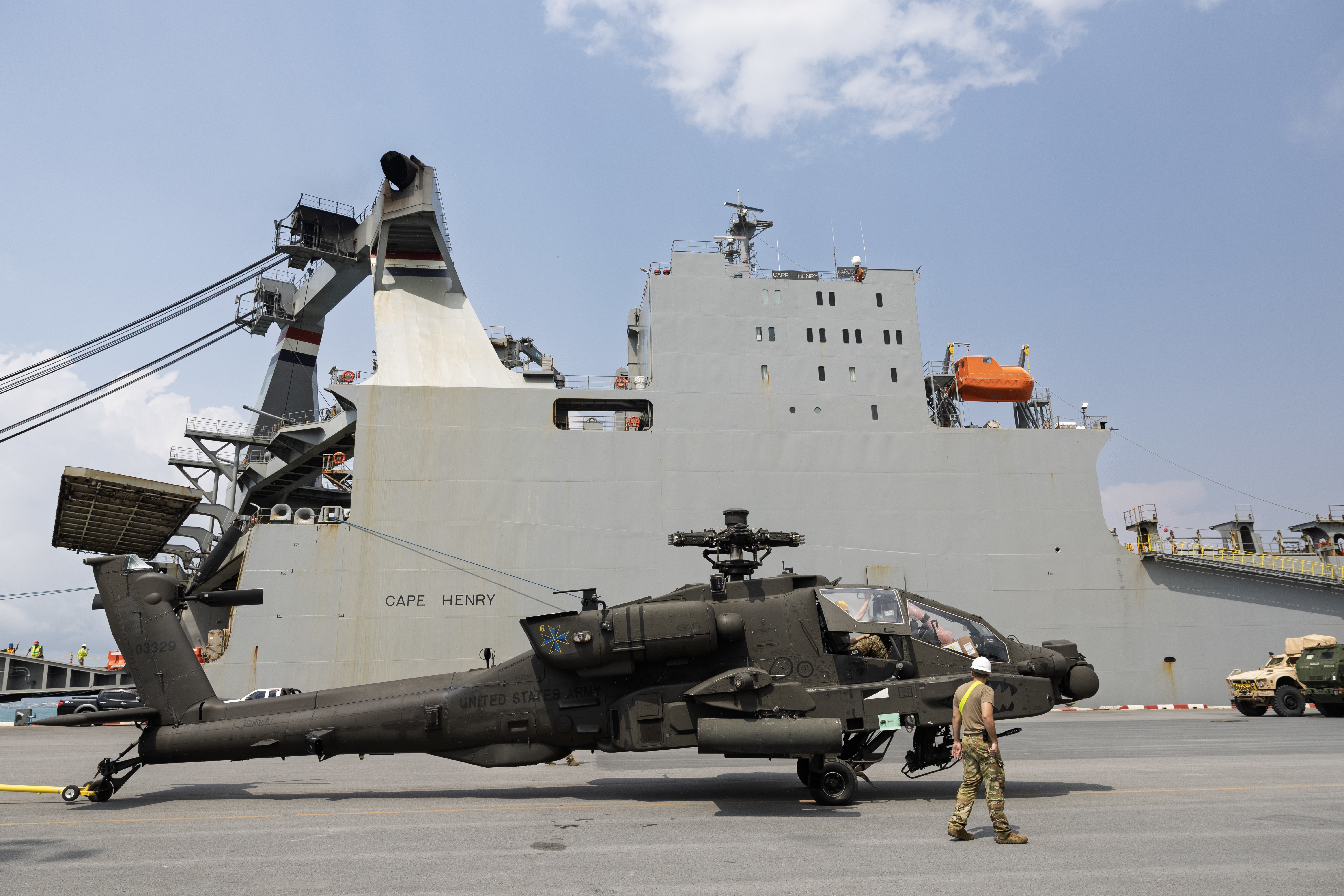 An AH-64 Apache heavy attack helicopter is staged next to Military Sealift Command (MSC) chartered Motor Vessel Cape Henry (T-AKR 5067) at the pier in Sattahip, Thailand, Feb. 18, during an offload of equipment that will be used in Joint Exercise Cobra Gold 2025.