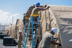 U.S. Airmen assigned to the 156th Civil Engineer Squadron, Puerto Rico Air National Guard, secure a tent outer tarp during a Disaster Relief Beddown System build up at Muñiz Air National Guard Base, Carolina, Puerto Rico, Feb. 27, 2025. The 156th CES Airmen assembled the DRBS, which can shelter 150 people in case of a disaster, as a training opportunity in preparation for the March regularly scheduled drill.