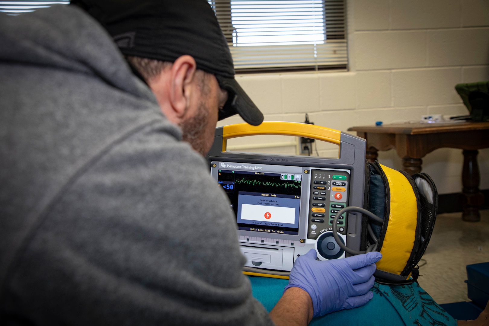 250303-N-KC192-1107 SPRING LAKE, N.C. (Mar. 3, 2025) - Hospital Corpsman 1st Class Axel Narvaez, the regional training officer assigned to Naval Medical Forces Atlantic (NMFL),  prepares a simulation defibrillator during a training scenario during a paramedic training scenario at Fayetteville Technical Community College, Mar. 3, 2025. The primary purpose of the 20-week joint military paramedic course at Fayetteville Technical Community College in Spring Lake, North Carolina is to expand the skills of service members, and increase survivability of those in harm’s way. Navy Medicine is enhancing Expeditionary Medical Unit (EXMED) capabilities by equipping Hospital Corpsmen with advanced trauma and pre-hospital care skills through an accelerated paramedic training program. This intensive five-month course ensures corpsmen are prepared to deliver life-sustaining care in austere environments, strengthening the Navy’s ability to support warfighters in operational settings worldwide. (U.S. Navy photo by Mass Communication Specialist 2nd Class Levi Decker)