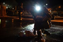 Airman in MOPP gear stands over training dummy on ground
