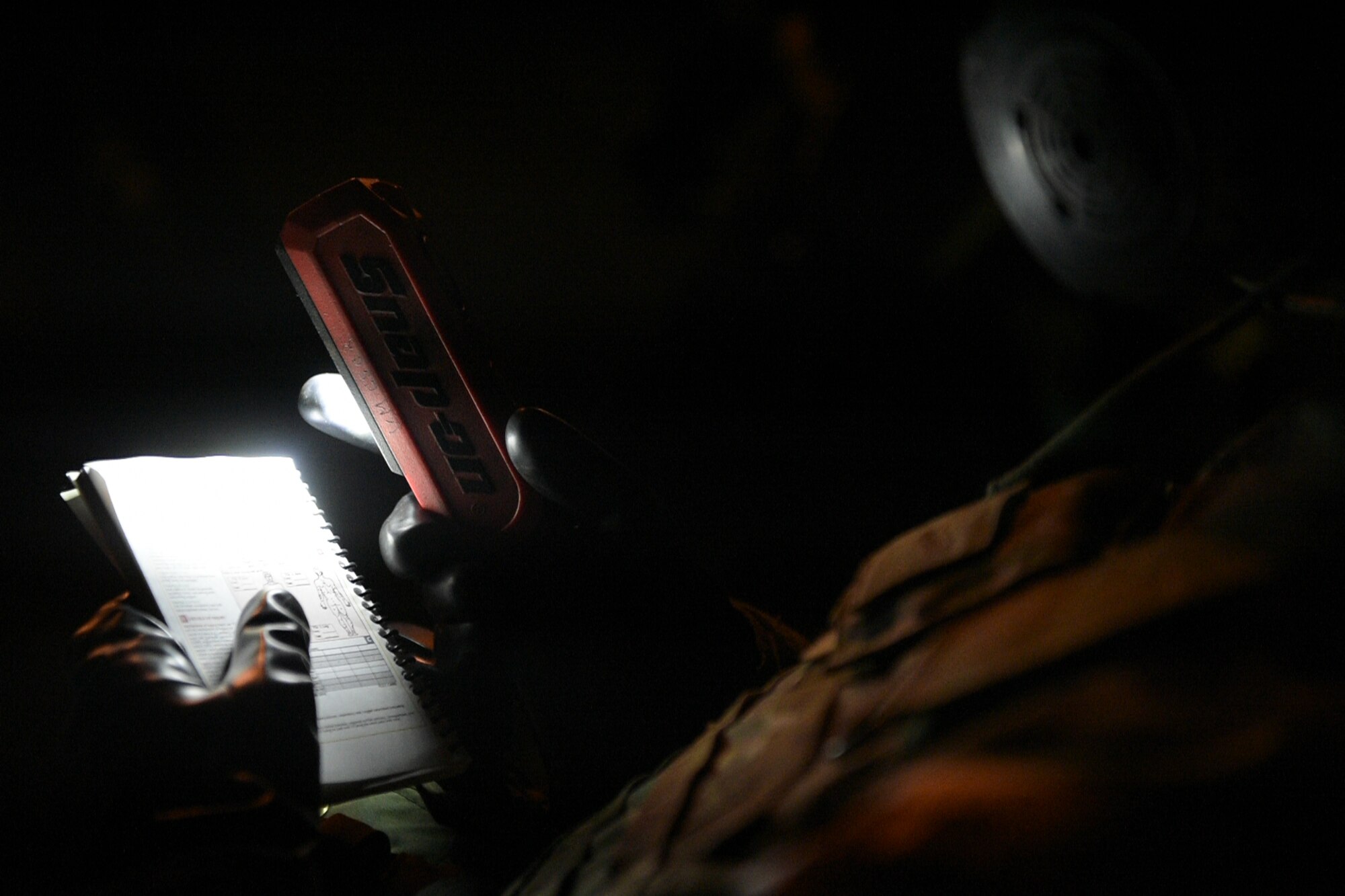 handheld field manual held by Airman