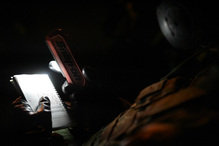 handheld field manual held by Airman