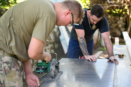 U.S. Army Staff Sgt. Austin Welk, assigned to the 829th Engineer Vertical Construction Company, 724th Engineer Battalion, 157th Mobilization Enhancement Brigade, Wisconsin Army National Guard, cuts boards with Royal Australian Air Force Leading Aircraftman Daniel Shaw, assigned to the 65th Air Base Recovery Squadron, to create new kitchen cabinets for base housing at the Air Transport Wing in Port Moresby, Papua New Guinea, March 13, 2025.