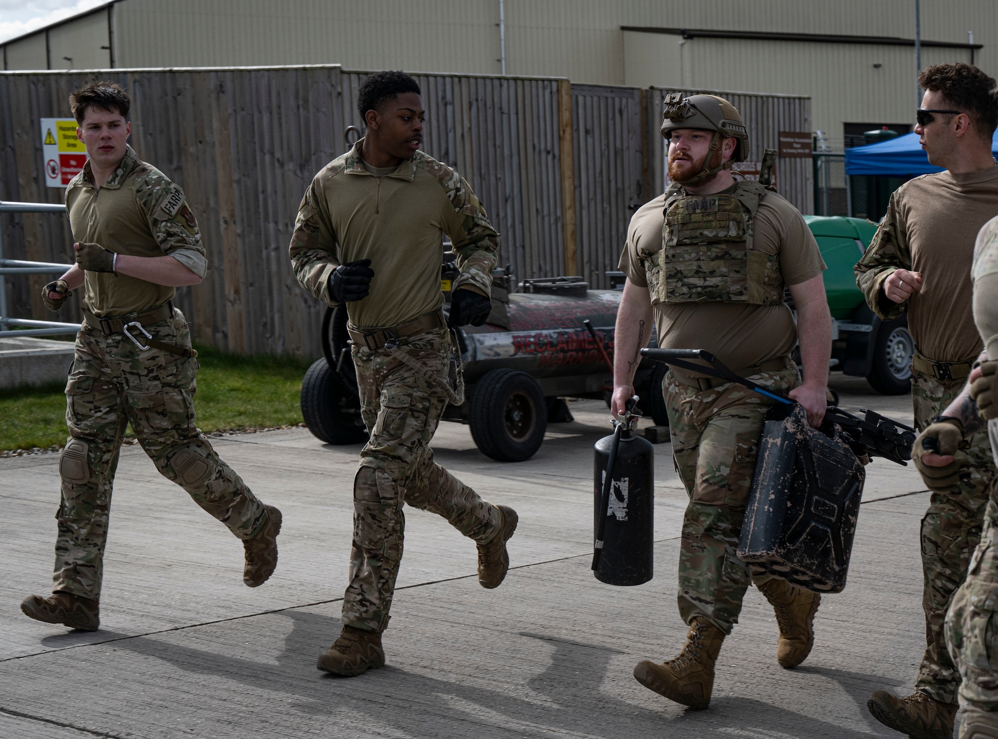 U.S. Air Force Senior Airman Clint Helgoth, center right, 100th Logistics Readiness fuels facilities technician, carries equipment while jogging during his forward area refueling point team tryout at RAF Mildenhall, England, March 14, 2025.